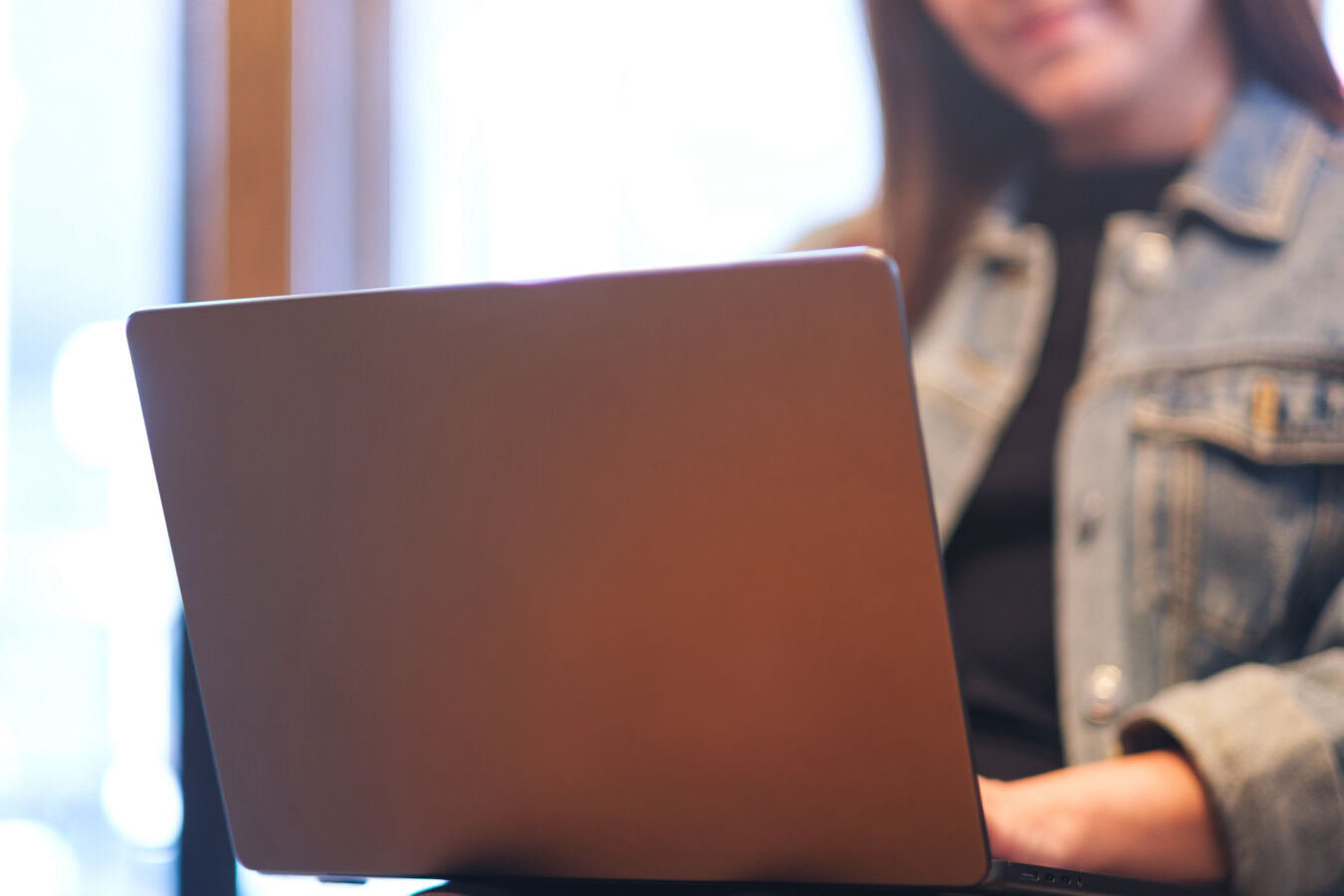 Closeup image of a young woman using and working on laptop computer in cafe